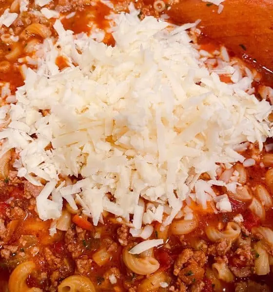 Adding the grated white cheddar cheese to goulash