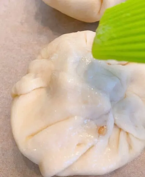 Brushing the pastry covered apples with egg wash.