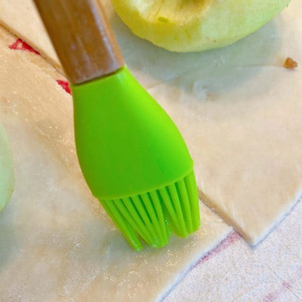 Pastry brush, brushing the perimeter of each dough square with egg wash.