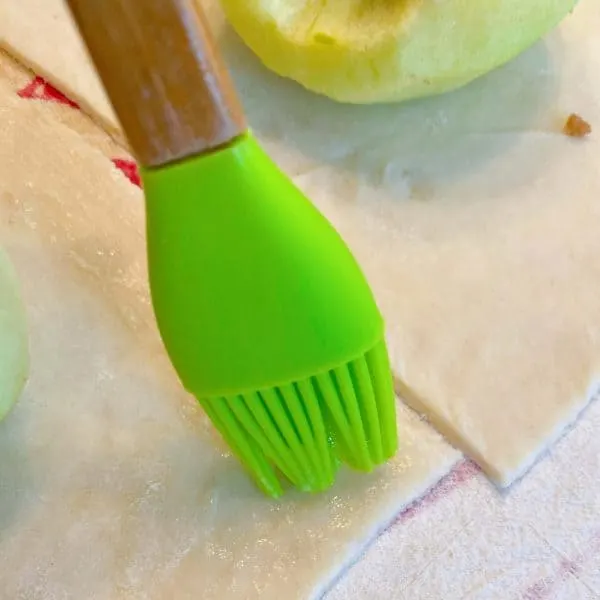 Pastry brush, brushing the perimeter of each dough square with egg wash.