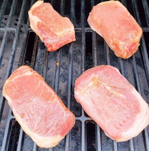 Pork chops on a prepared grill cooking.