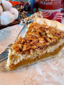 Close up of slice of Caramel Pecan Cheesecake Pie on a plate with a fork