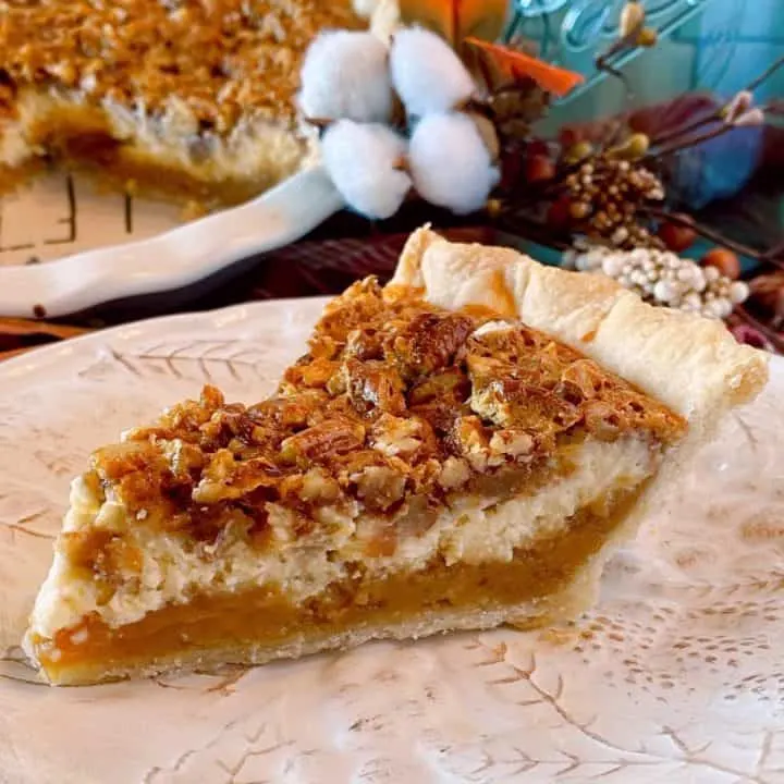 Slice of Caramel Pecan Cheesecake Pie on a tan plate with full pie in the background.