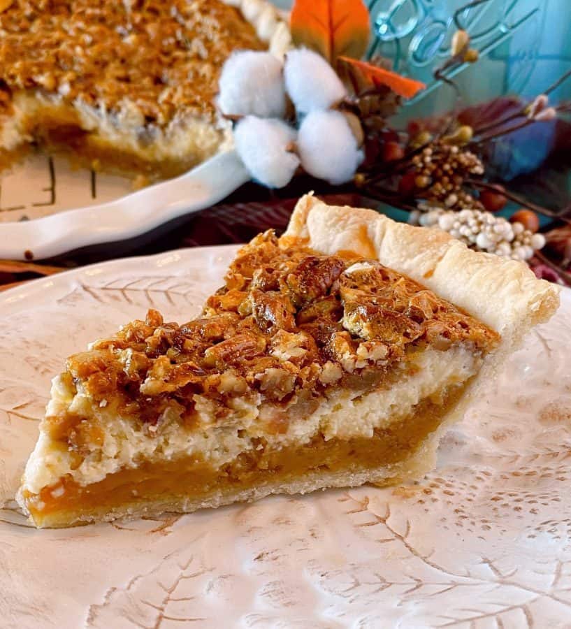 Slice of Caramel Pecan Cheesecake Pie on a tan plate with full pie in the background.