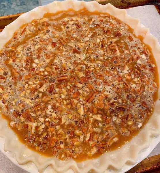 pie covered in caramel sauce on baking sheet ready for the oven.