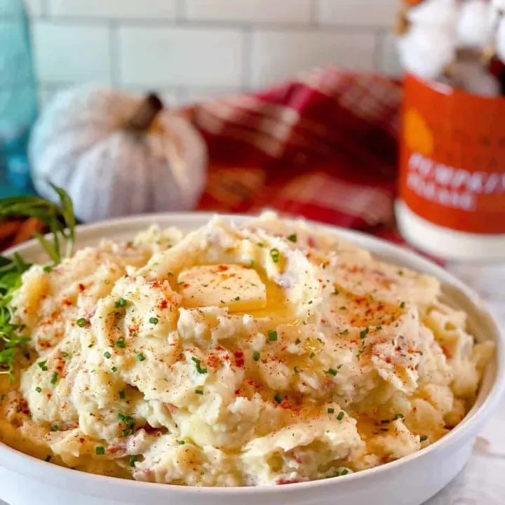Bowl full of Savory Herbed Mashed Potatoes with butter and fresh herbs.