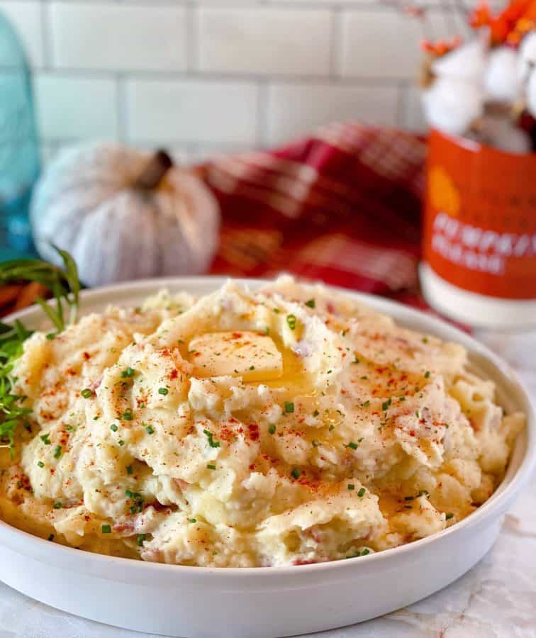 Bowl full of Savory Herbed Mashed Potatoes with butter and fresh herbs.