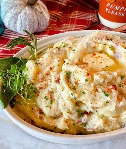 Close up photo of bowl filled with creamy instant pot mashed potatoes with fresh herbs.