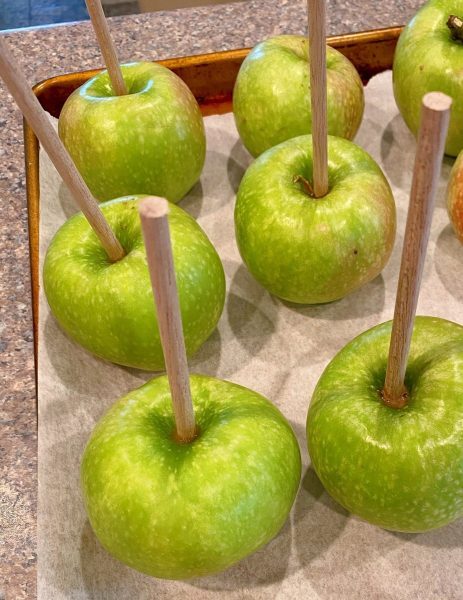 Apples, washed, dried, and sticks placed in the center on a parchment lined baking sheet.