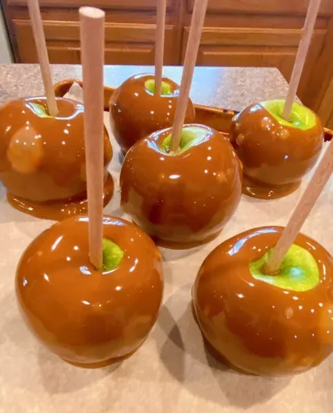 Apples dipped in caramel and placed back on a lined baking sheet.