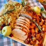 Herb Crusted Turkey Roast on a platter with roasted squash and stuffing.
