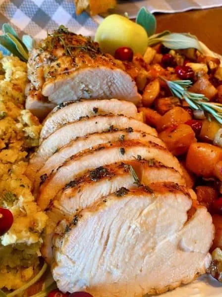 Turkey Roast sliced into slices and placed on a platter with squash and stuffing.