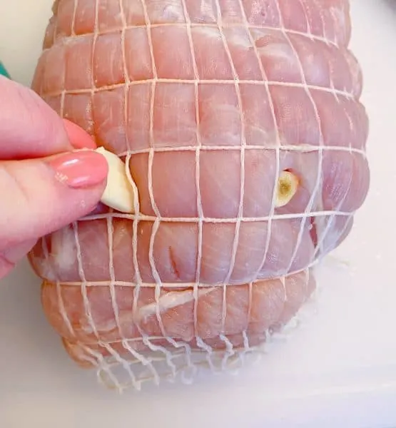 Inserting garlic cloves into the cuts of the Turkey Roast.