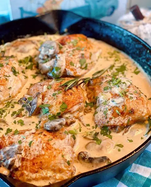 Chicken thighs fully cooked in wine mushroom sauce spooned over chicken
