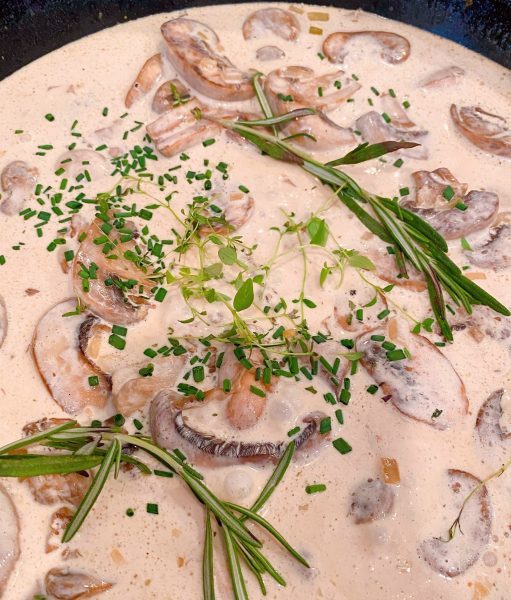 Adding herbs to mushroom sauce.