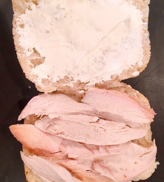 ciabatta roll cut in half length wise and topped with cream cheese spread and turkey.