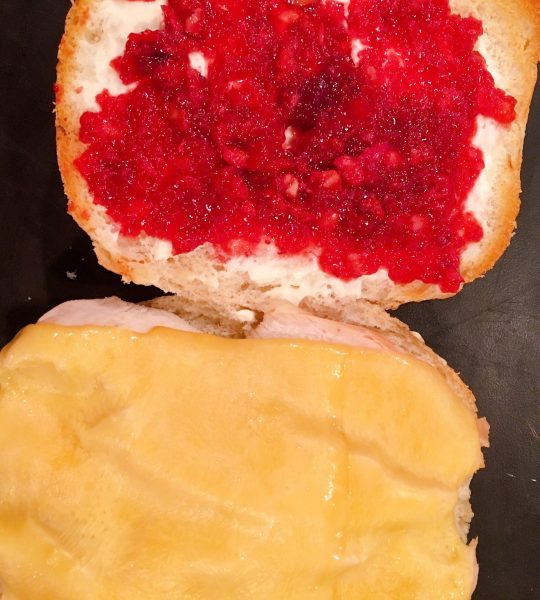 Turkey sandwich with melted gouda cheese adding cranberry sauce.