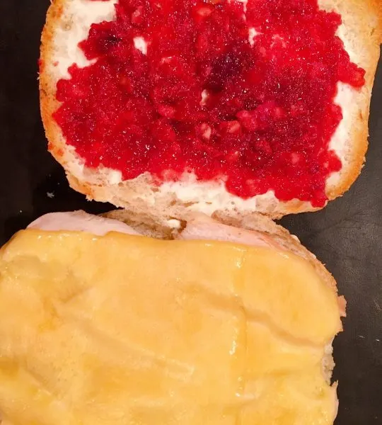 Turkey sandwich with melted gouda cheese adding cranberry sauce.