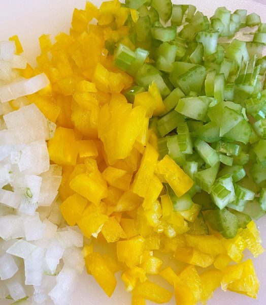 cutting board with chopped celery, onions, and peppers.