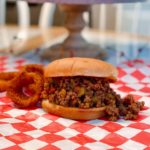 Easy Sloppy Joes on a checkered mat with onion rings