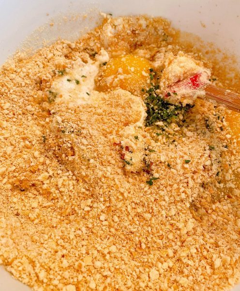 Adding cracker crumbs to crab cake ingredients.
