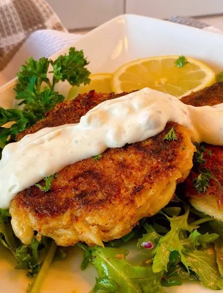 Crab cake with tartar sauce drizzled over the top