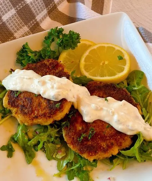 Crab Cakes with Tartar sauce and arugula salad on a plate