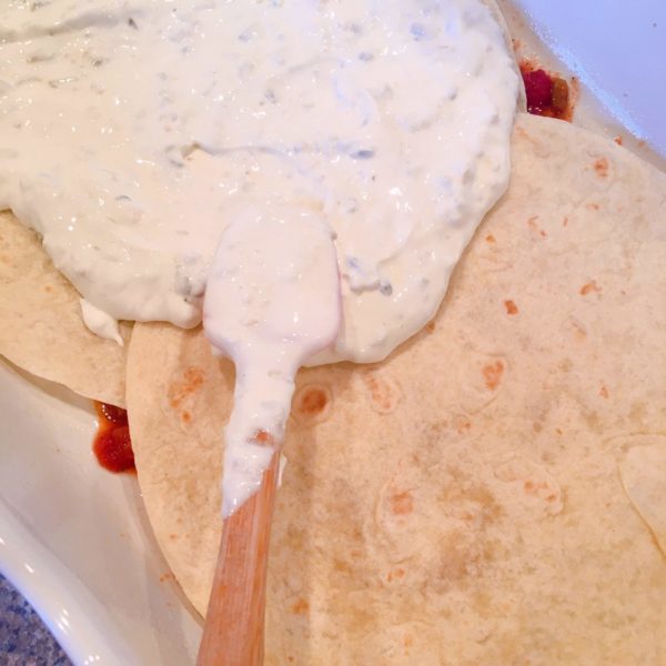 Spreading sour cream mixture on top of flour tortillas.