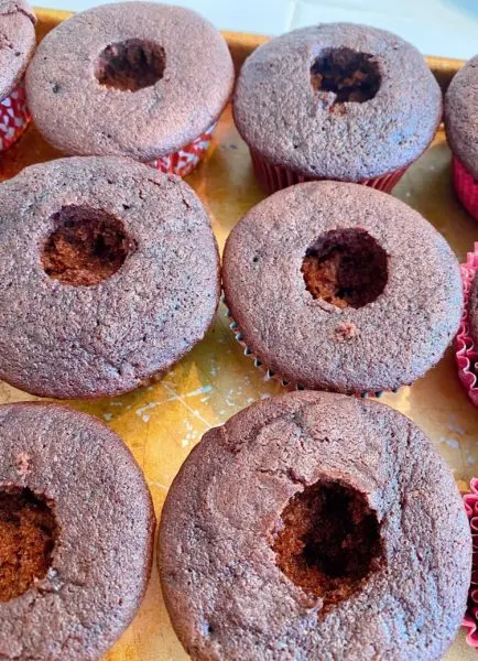 Placing a hole in the center of each cupcake. 