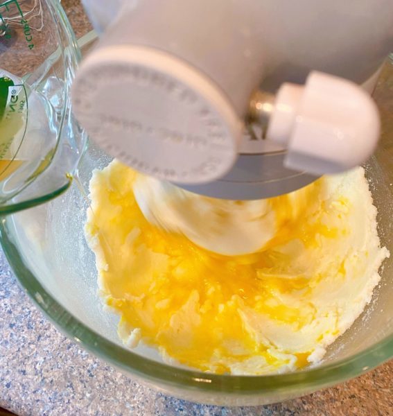 Adding eggs into butter and sugar in mixing bowl