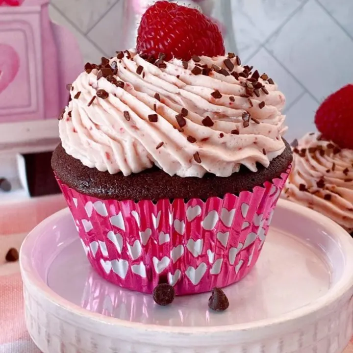 Chocolate Raspberry Cupcake on a mini cake stand topped off with a fresh raspberry.