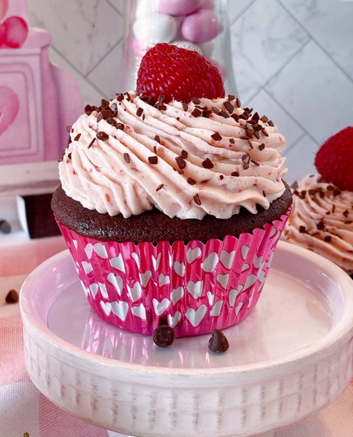 Chocolate Raspberry Cupcake on a mini cake stand topped off with a fresh raspberry.