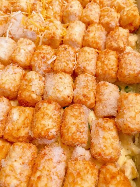 placing frozen tater tots on top of the chicken mixture in the casserole dish