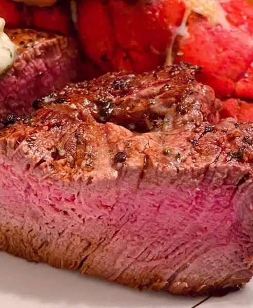 Medium Filet Mignon on serving platter sliced in half to reveal the inside of the steak.