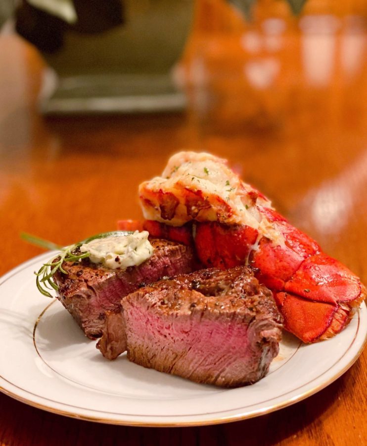 Filet Mignon cut open next to an air fried lobster tail on a serving plate.