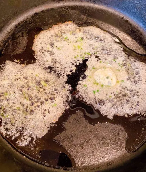 Cast Iron Skillet with Herbed butter on the stove top. 