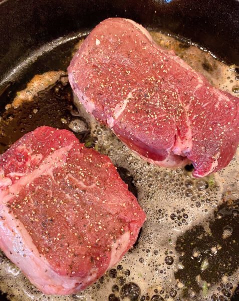 Steaks in the hot skillet searing.