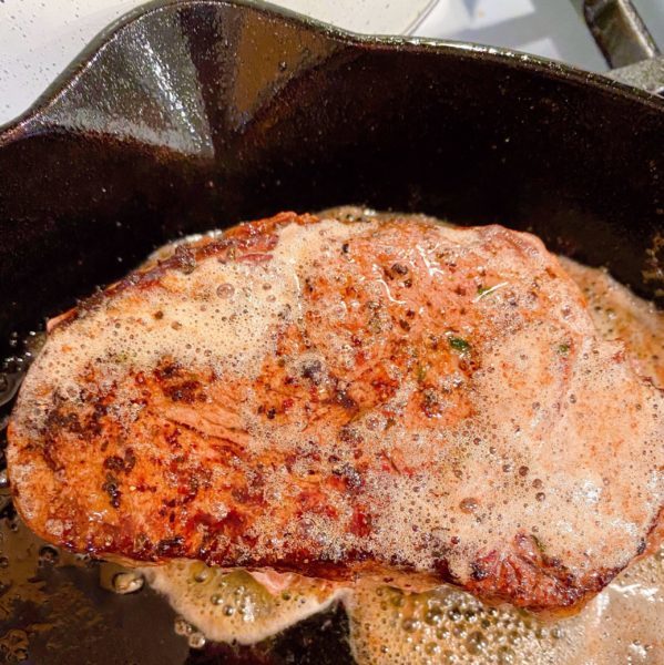 Steaks going in the oven in the cast iron skillet.