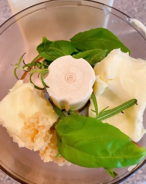 Butter and herbs in food processor waiting to be processed.