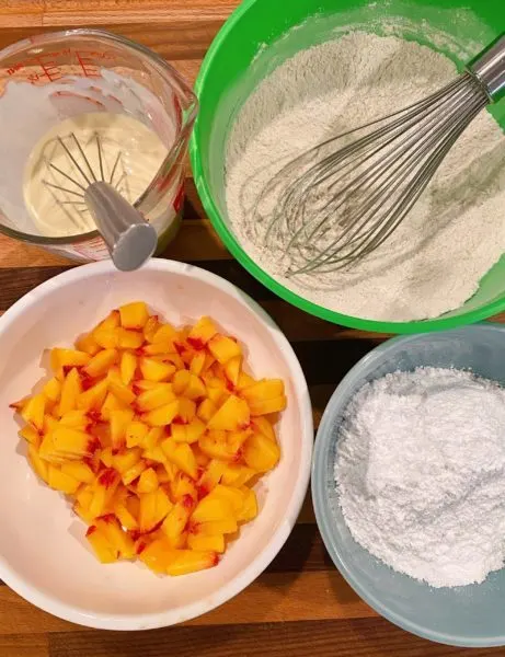 Wet, dry ingredients and peaches for peach fritters.