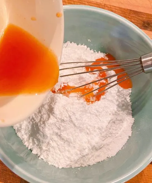 Adding peach juice into the confectioners sugar to make glaze.