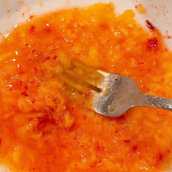 fresh peaches mashed into a bowl for the glaze.