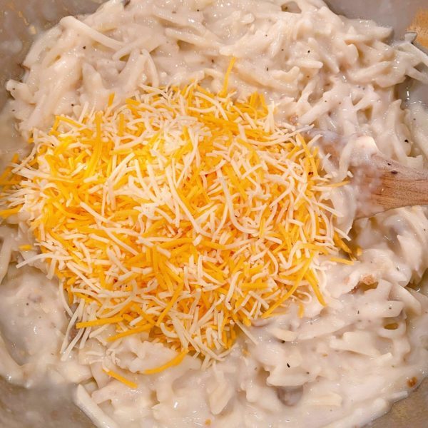 Adding cheese to potato ingredients in mixing bowl.
