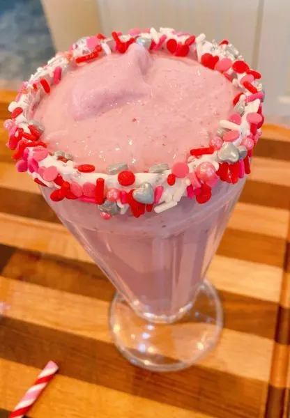 Pretty milkshake glass filled with raspberry white chocolate milkshake just below the rim.