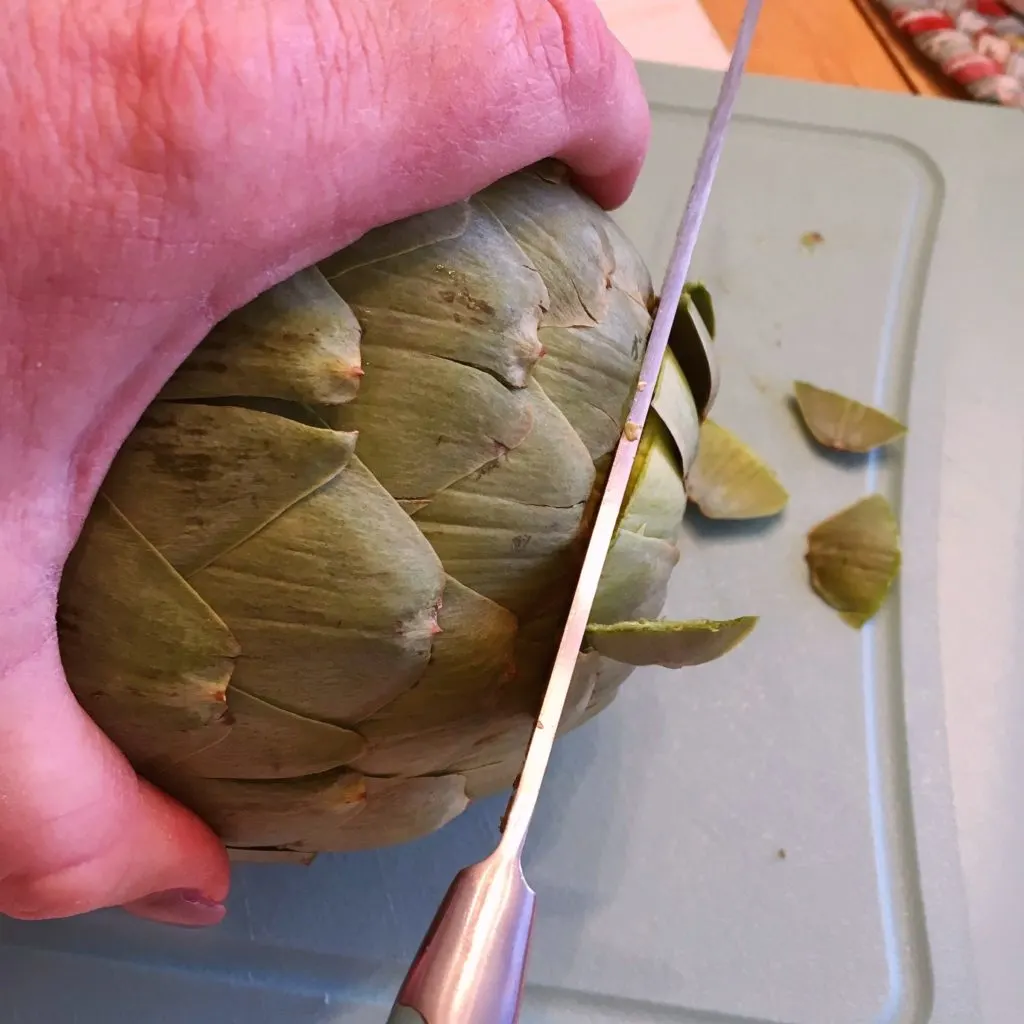 Removing the top of the artichoke.