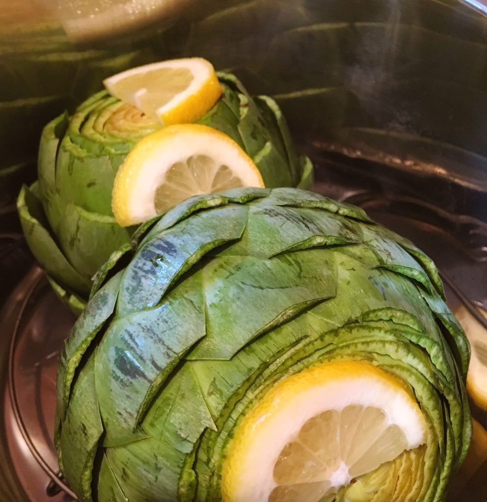 Artichokes in instant pot with lemon slices.