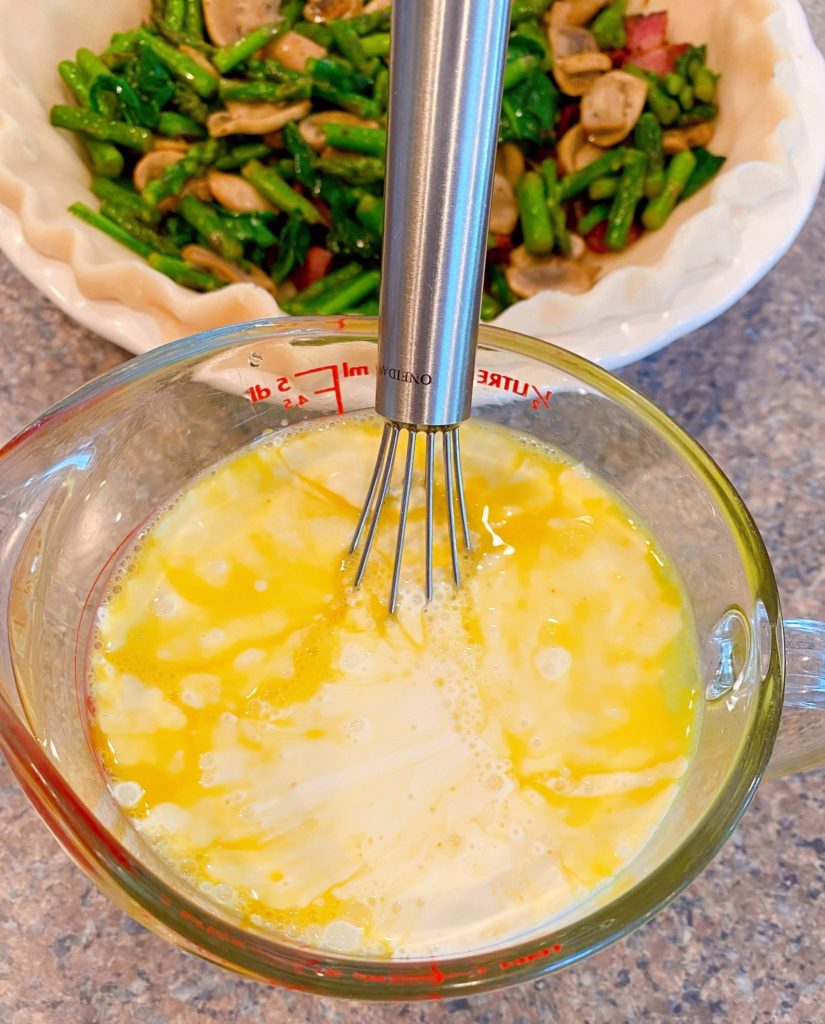 Mixing bowl with four eggs, half-and-half cream, salt, pepper, onion powder, and garlic powder.