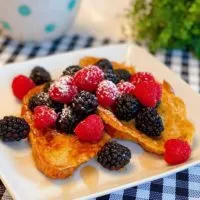 Croissant French Toast with fresh berries on a square white plate.