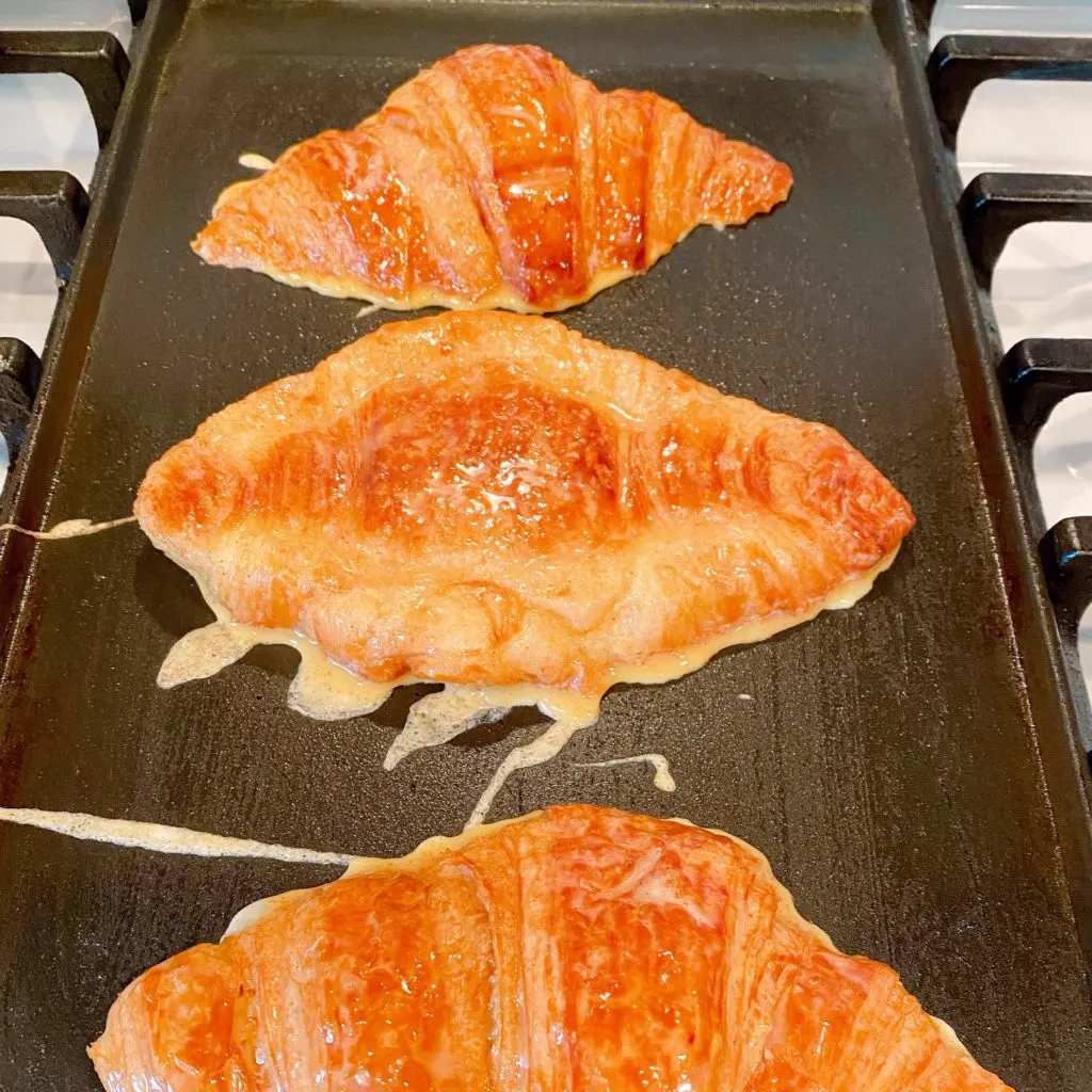 Croissant French Toast cooking on a griddle.