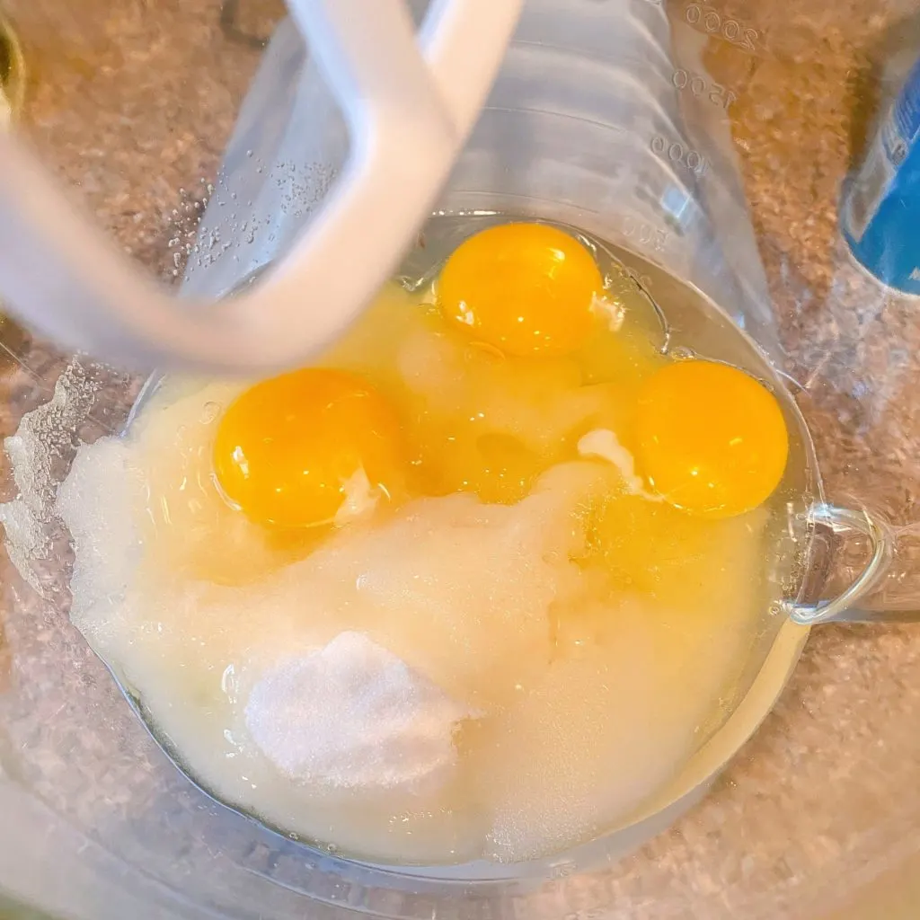 Sugar, eggs, vanilla, and vegetable oil in mixing bowl of kitchen aid mixer.